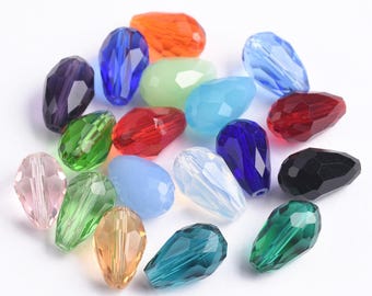 May include: Assortment of colorful glass teardrop beads in various shades of blue, green, red, pink, and clear. The beads are faceted and have a pearlescent finish.