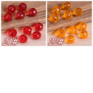 May include: Two sets of faceted glass beads, one set is red and the other is orange. The beads are arranged in a semi-circle on a wooden surface. The text "21#" and "22#" are printed below each set of beads.