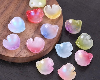 May include: A collection of iridescent, petal-shaped beads in various colors, including pink, blue, yellow, and green. The beads have a glossy finish and are arranged on a wooden surface, suitable for jewelry making or craft projects.