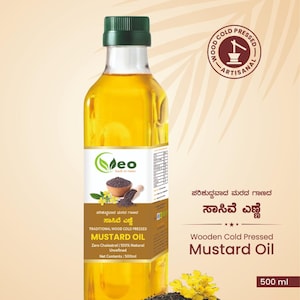 Puede incluir: Una botella de 500 ml de aceite de mostaza prensado en fr&iacute;o de madera Vasantha Eco & Organics. La botella es transparente y muestra el aceite amarillo en su interior. La etiqueta es blanca con acentos verdes y presenta el texto "ಸಾಸಿವೆ ಎಣ್ಣೆ" en escritura kannada, que se traduce como "Aceite de mostaza". La etiqueta tambi&eacute;n incluye el texto "Aceite de mostaza prensado en fr&iacute;o de madera tradicional" y "Cero colesterol | 100% natural sin refinar". La botella est&aacute; sobre una superficie de madera con semillas de mostaza esparcidas a su alrededor.