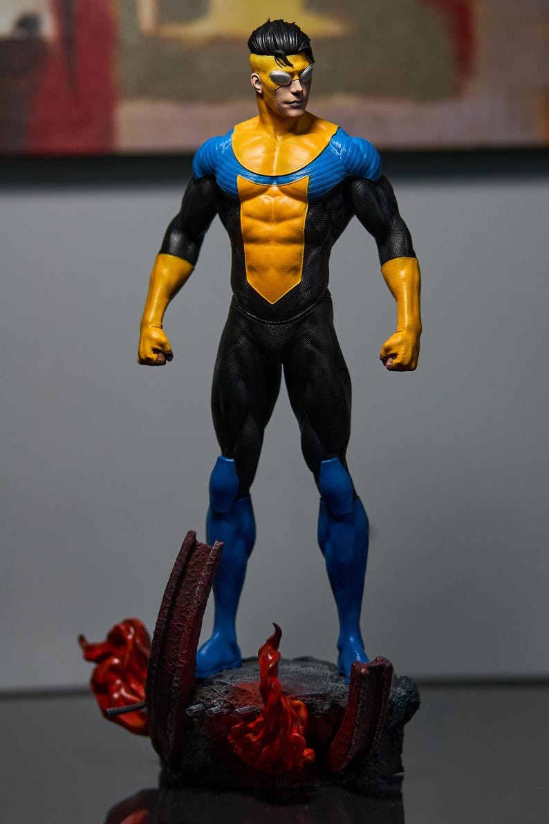 May include: A figurine of a superhero in a dynamic pose. The figure is clad in a black suit with yellow and blue accents. The base features a rocky terrain with red and orange flame details, adding a dramatic effect to the collectible.
