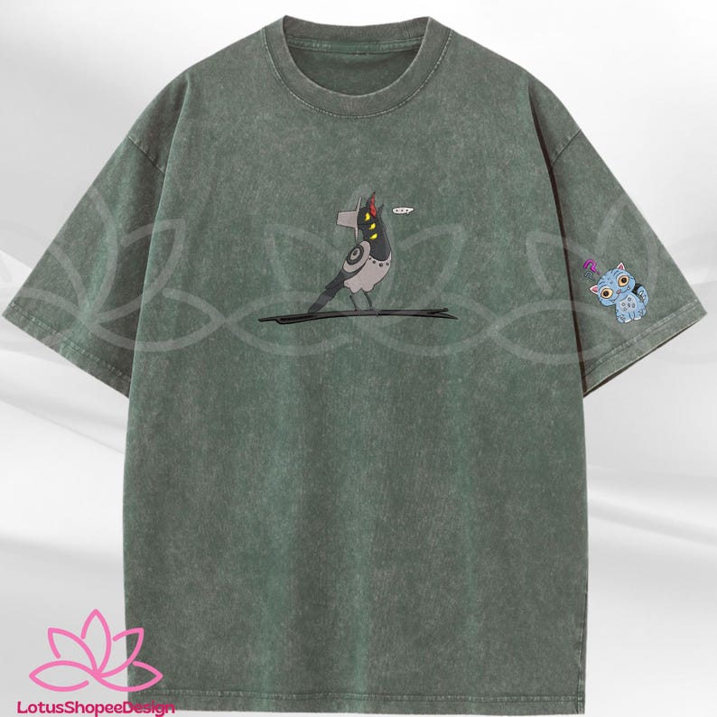 May include: Green t-shirt with a graphic of a bird with a speech bubble and a small blue cat on the sleeve. The shirt has a crew neck and short sleeves. The bird is gray, black, and white.