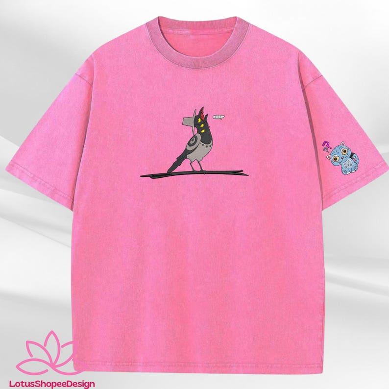 May include: Pink t-shirt featuring a cartoon bird perched on a branch, with a speech bubble. The sleeve has a blue owl graphic with a question mark. The shirt has a crew neck and short sleeves.