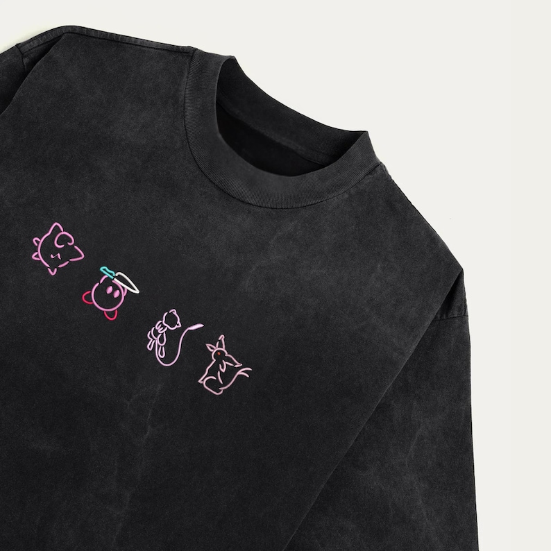 May include: Black long-sleeved top with a crew neck. The shirt displays a series of neon pink and green cartoon character outlines. The garment has a faded, vintage appearance.