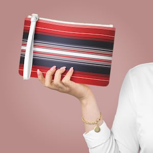 May include: A red and white striped clutch with a white strap. The clutch has a navy blue stripe pattern.