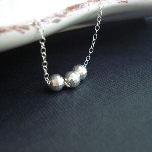 May include: A silver necklace with three faceted silver beads.