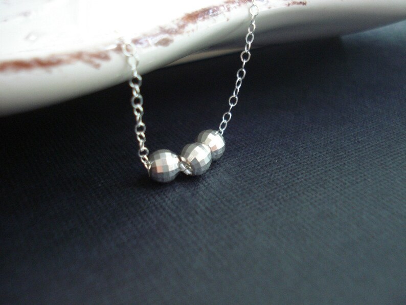 May include: A silver necklace with three faceted silver beads.