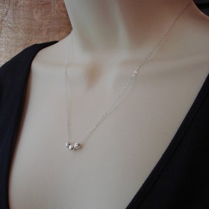 May include: A silver chain necklace with three small silver beads.