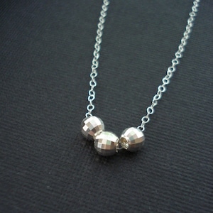 May include: A silver necklace with three faceted silver beads.