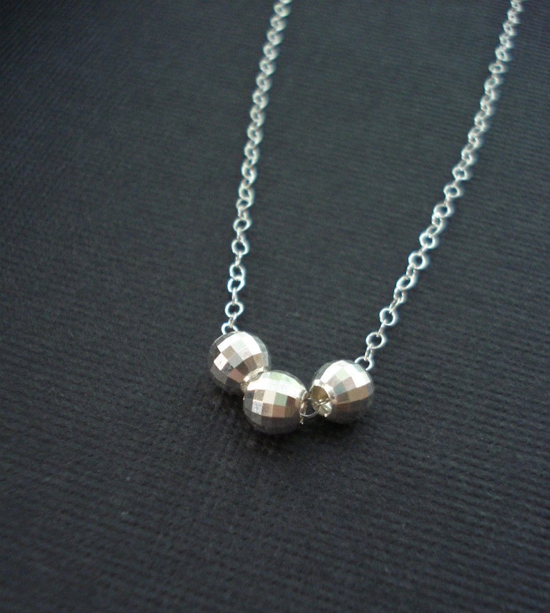 May include: A silver necklace with three faceted silver beads.
