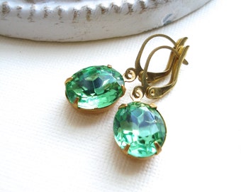 May include: A pair of gold earrings with green oval-shaped gemstones. The earrings have a simple design and are perfect for everyday wear.