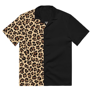 May include: Short-sleeved button-down shirt. One side features a leopard print in tan and brown, while the other side is solid black. The shirt has a classic collar and a relaxed fit, suitable for casual wear.