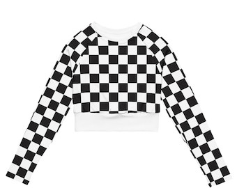 May include: A long-sleeved crop top featuring a black and white checkerboard pattern. The top has a white crew neck and a white band at the waist. The sleeves extend to the wrists, and the overall design is a bold, graphic statement.