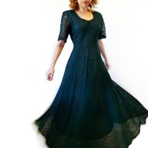 May include: A long, dark green lace dress with a scoop neckline and short sleeves. The dress has a flowing skirt and is perfect for a formal occasion.