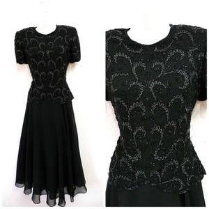 May include: Black formal dress with short sleeves and a knee-length skirt. The bodice is heavily embellished with intricate silver beading in a swirling floral pattern. The skirt has a flowing, layered design.