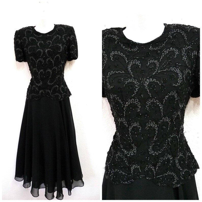 May include: Black formal dress with short sleeves and a knee-length skirt. The bodice is heavily embellished with intricate silver beading in a swirling floral pattern. The skirt has a flowing, layered design.