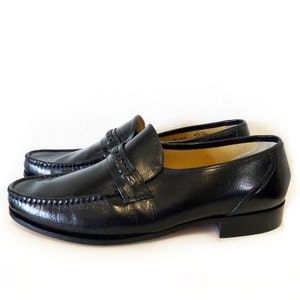 Pode incluir: Sapatos de couro preto com um detalhe de costura decorativo em torno da ponta e uma &uacute;nica tira no peito do p&eacute;.