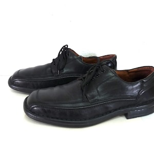 May include: A pair of black leather lace-up shoes with a stitched design on the toe and a slightly raised heel.