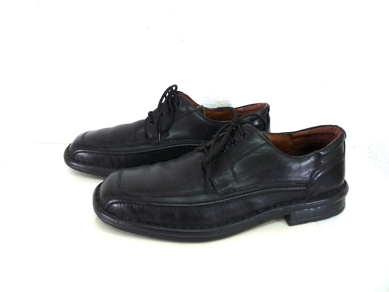 May include: A pair of black leather lace-up shoes with a stitched design on the toe and a slightly raised heel.