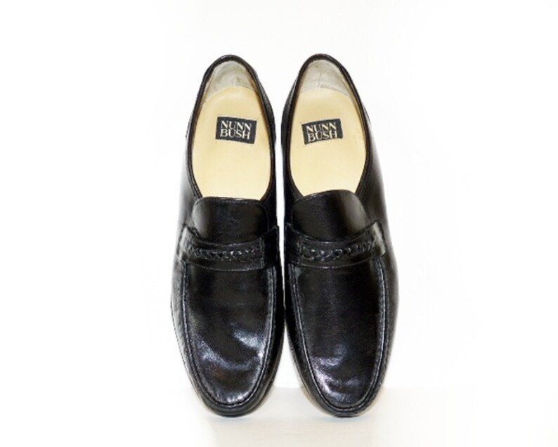 Pode incluir: Um par de mocassins pretos de couro Nunn Bush com um detalhe tran&ccedil;ado na frente.