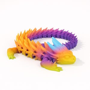 Peut inclure: Un jouet dragon articulé multicolore aux tons de jaune, orange, violet et bleu. Le dragon a une colonne vertébrale épineuse détaillée et un corps incurvé. Le jouet est conçu pour être flexible et mobile.