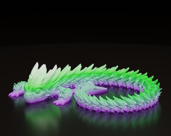 May include: A 3D-printed dragon figurine in shades of green, purple, and white. The dragon is lying down, with its body curved and its head facing forward. The figurine has a detailed, textured design.