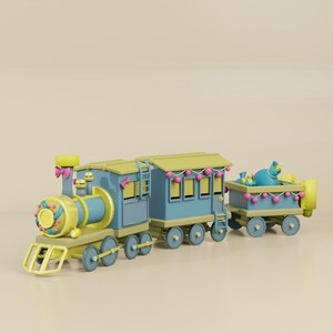 May include: A whimsical toy train in shades of blue and yellow, with pink accents. The train features a locomotive, passenger car, and a cargo car, all decorated with festive details. The cargo car carries a blue sack.