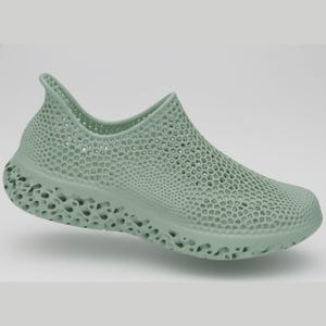 Puede incluir: Un zapato sin cordones de color verde claro con un diseño único de tejido abierto. El zapato presenta una suela texturizada y una parte superior transpirable, ideal para uso casual. El zapato está hecho de un material flexible.