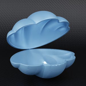 May include: A light blue, cloud-shaped container with a hinged lid. The container is open, revealing the interior. The design is smooth and glossy, with rounded edges. The background is a dark, textured surface.