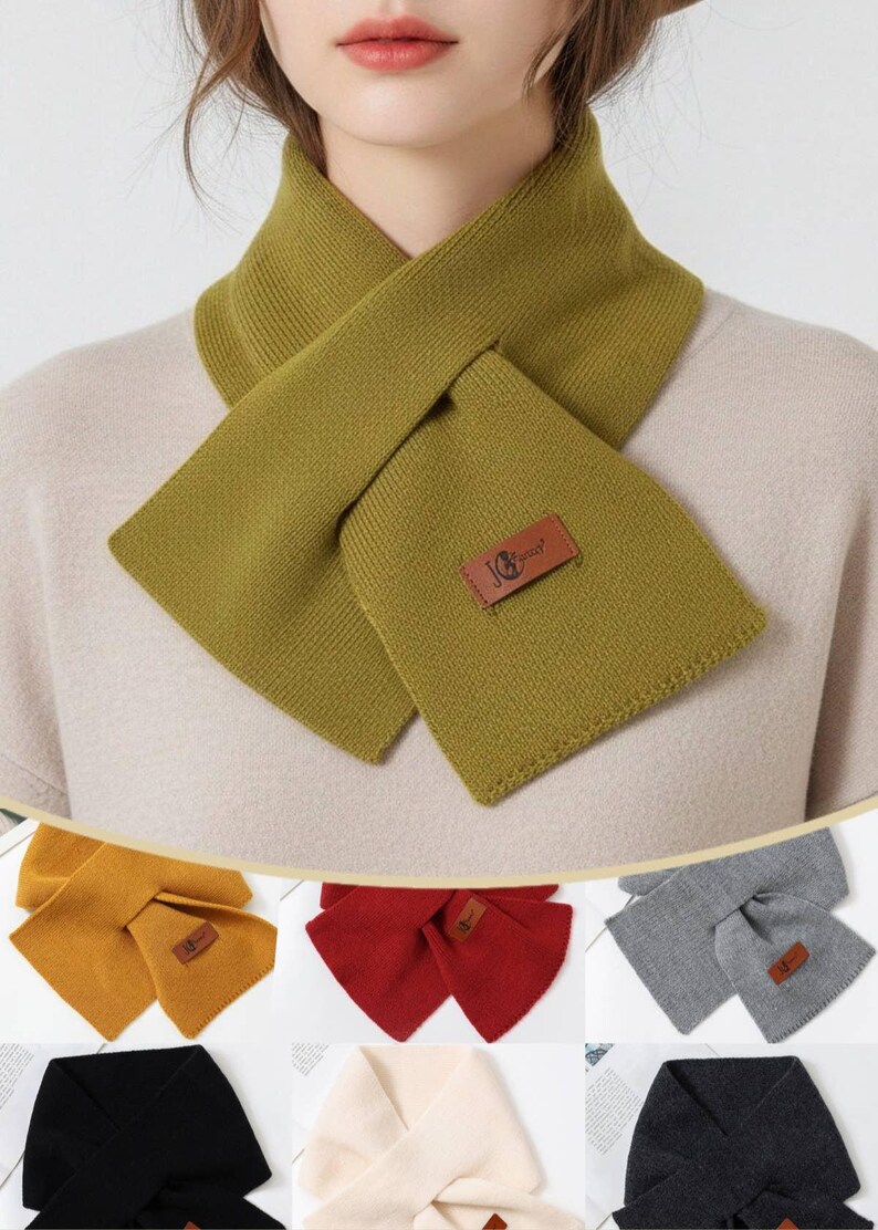 Puede incluir: Bufanda de punto verde oliva con dise&ntilde;o cruzado. La bufanda presenta un parche rectangular con un logotipo. Tambi&eacute;n se muestran bufandas adicionales en amarillo mostaza, rojo, gris, negro y crema.