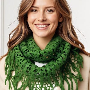 May include: A green, open-weave crochet scarf with fringe. The scarf is a vibrant shade of green and has a textured, lacy design. The fringe hangs down from the bottom edge of the scarf. The scarf is worn around the neck.
