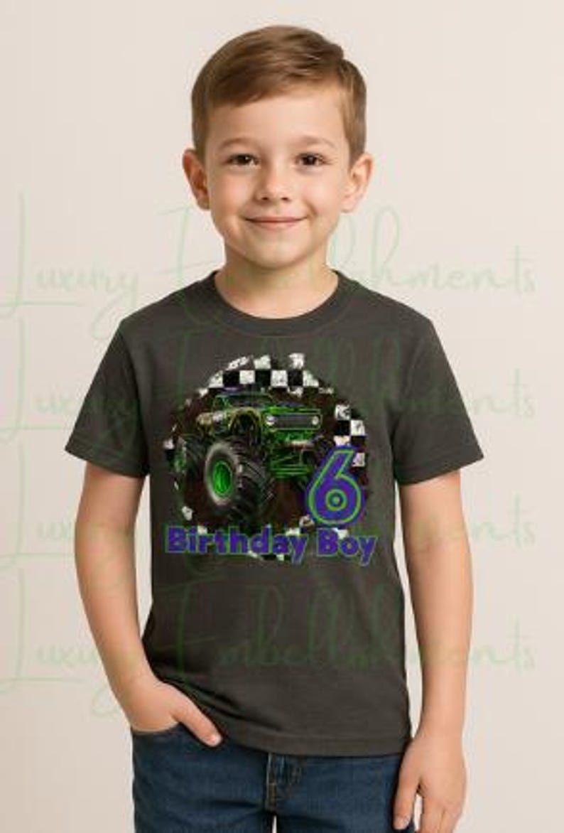 K&ouml;nnte beinhalten: Ein dunkelgraues T-Shirt mit einem gr&uuml;nen Monstertruck-Design, der Zahl 6 und dem Text "Birthday Boy" in Blau und Gr&uuml;n. Das T-Shirt wird von einem jungen Mann in blauen Jeans getragen.