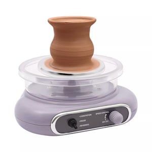 May include: A purple pottery wheel with a clear plastic base and a clay pot on top. The wheel has a speed control knob and a switch with the labels "Corotation", "Pause", and "Reverses".