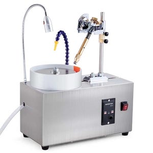 May include: A silver metal lapidary machine with a white grinding wheel, a flexible blue water tube, and a gooseneck lamp. The machine has a control panel with the word "INVERTER" and a red power switch. It is designed for precision gemstone cutting.