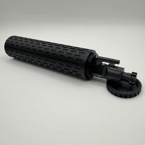May include: A black cylindrical case with a textured surface, open to reveal a black multi-tool with a KAK logo. The case has a black lid with a textured edge.