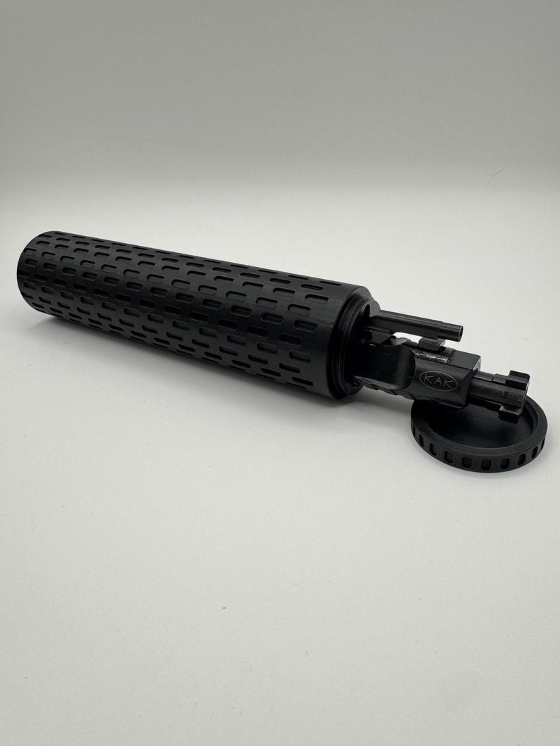 May include: A black cylindrical case with a textured surface, open to reveal a black multi-tool with a KAK logo. The case has a black lid with a textured edge.