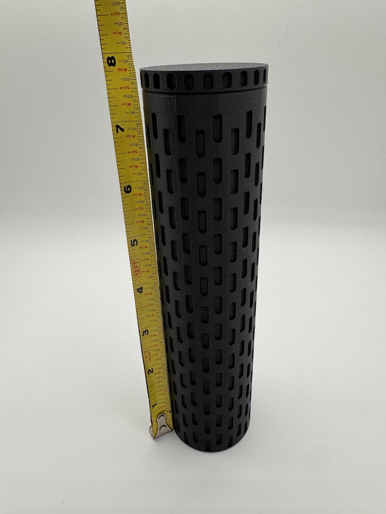 May include: A black cylindrical container with a patterned design. The container is approximately 8 inches tall.