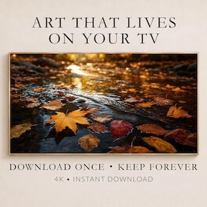 May include: A digital television display showing a landscape photograph of autumn leaves floating in a flowing stream. The text reads: ART THAT LIVES ON YOUR TV, DOWNLOAD ONCE • KEEP FOREVER, 4K • INSTANT DOWNLOAD. The frame is thin and metallic.