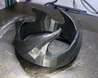 Könnte beinhalten: Eine schwarze, 3D-gedruckte Krone mit einem scharfen, kantigen Design. Die Krone ist aus Kunststoff und hat eine glatte, matte Oberfläche.