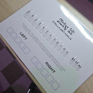 Può includere: Un kit di misurazione per unghie finte di Stella.BBT.Nails. Il kit include una fila di punte per unghie in plastica trasparente numerate da 0 a 41, e tre punte aggiuntive etichettate 8.5, 3.5 e 40.5. Il kit include anche due file di quadrati vuoti etichettati "SINISTRA" e "DESTRA" per selezionare la dimensione corretta per ogni dito.