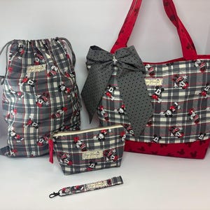 Puede incluir: Un conjunto de bolsos y accesorios de cuadros grises con un estampado de Minnie Mouse. El conjunto incluye una bolsa con cord&oacute;n, un bolso tote con un lazo grande, una peque&ntilde;a bolsa con cremallera y una pulsera. El bolso tote tiene detalles y asas rojas.