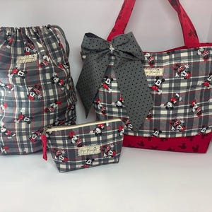 Puede incluir: Un conjunto de cuatro bolsas de tela a juego con un estampado de cuadros grises con detalles en rojo y dise&ntilde;os de Minnie Mouse. El conjunto incluye una bolsa con cord&oacute;n, un bolso tote con un lazo grande y una bolsa con cremallera. El bolso tote tiene asas rojas y una base roja.
