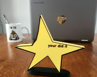 May include: A yellow star-shaped award with a black base and the text "you did it" on the front.