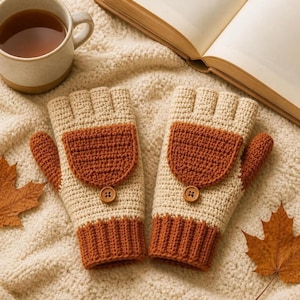 Peut inclure: Une paire de gants sans doigts au crochet en crème et orange brûlé. Chaque gant présente un poignet côtelé, une section de main en crème, un rabat texturé orange brûlé fixé par un petit bouton marron et un design sans doigts.