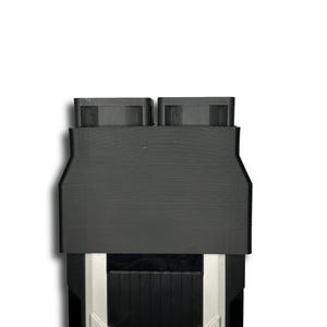 以下が含まれることがあります： 黒と緑の電子部品で、シルバーのアクセントが付いています。上部には2つの長方形の開口部があり、下部には格子状のデザインがあります。エッジはシルバーとグリーンで縁取られています。