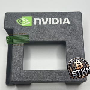 Peut inclure: Un support gris imprimé en 3D avec une découpe pour une carte graphique. Le support porte le logo NVIDIA et le texte "Veteran Owned Business" imprimé dessus. Un logo Bitcoin est imprimé sur le côté du support.