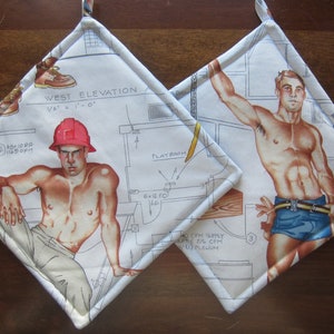 May include: Two white cotton pot holders with a blue trim. One pot holder features a drawing of a man in a red hard hat and a white tank top. The other pot holder features a drawing of a man in a blue tank top. Both pot holders have a blueprint design with text that reads "West Elevation 1/8" = 1'-0" and "Playroom".