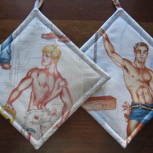 May include: Two white cotton pot holders with a diamond shape. One features a man with a muscular build wearing blue jeans and holding a saw. The other features a man with a muscular build wearing blue swim trunks and holding a chain. Both pot holders have a white background with black text and illustrations.