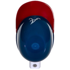 May include: A baseball cap night light with a red bill and a blue cap. The cap has a white logo on the front. The night light has a white base.