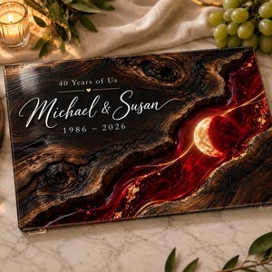 May include: A rectangular glass serving board featuring a dark wood grain pattern on the left and a swirling deep red and gold resin river design on the right. The text reads 40 Years of Us, Michael & Susan, and the years 1986 - 2026.